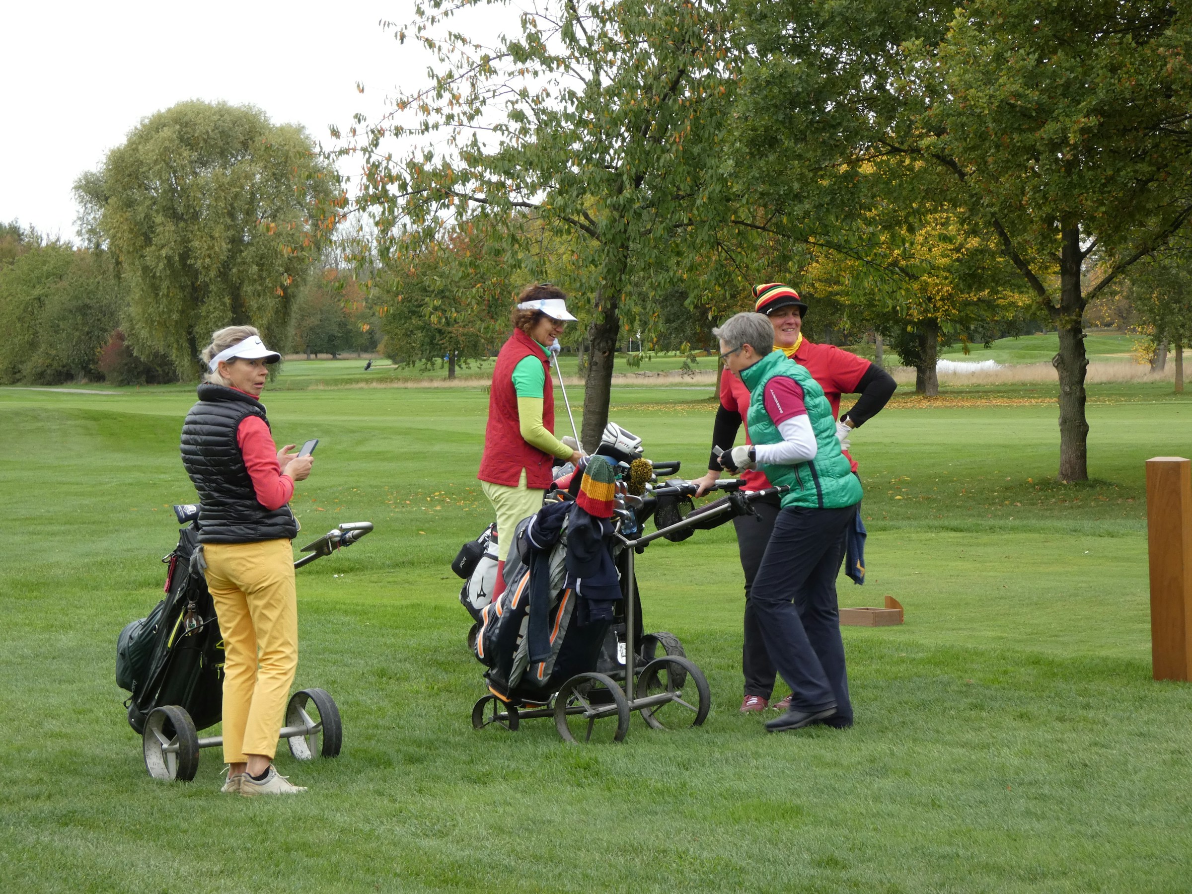 A group of friends gathered around their golf bags on a course