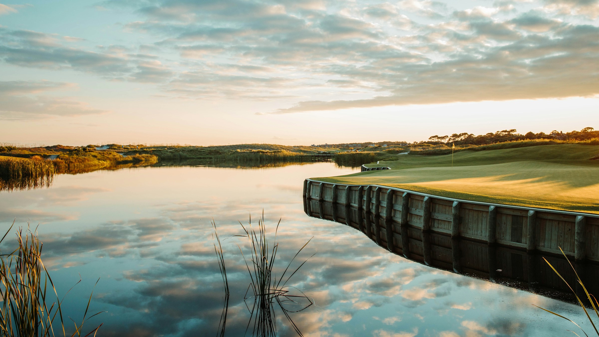 A wooden dock on a quiet lake at a coastal golf course at dusk
